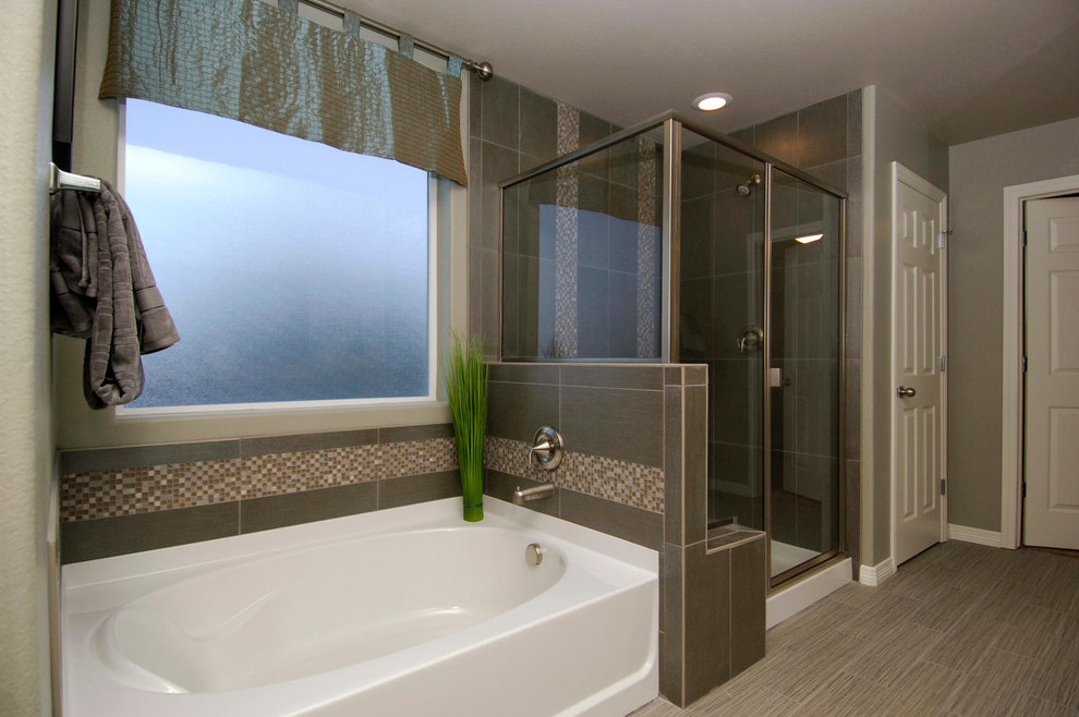 Cette photo montre une salle de bain chic avec une baignoire en alcôve, une douche d'angle et un carrelage gris.