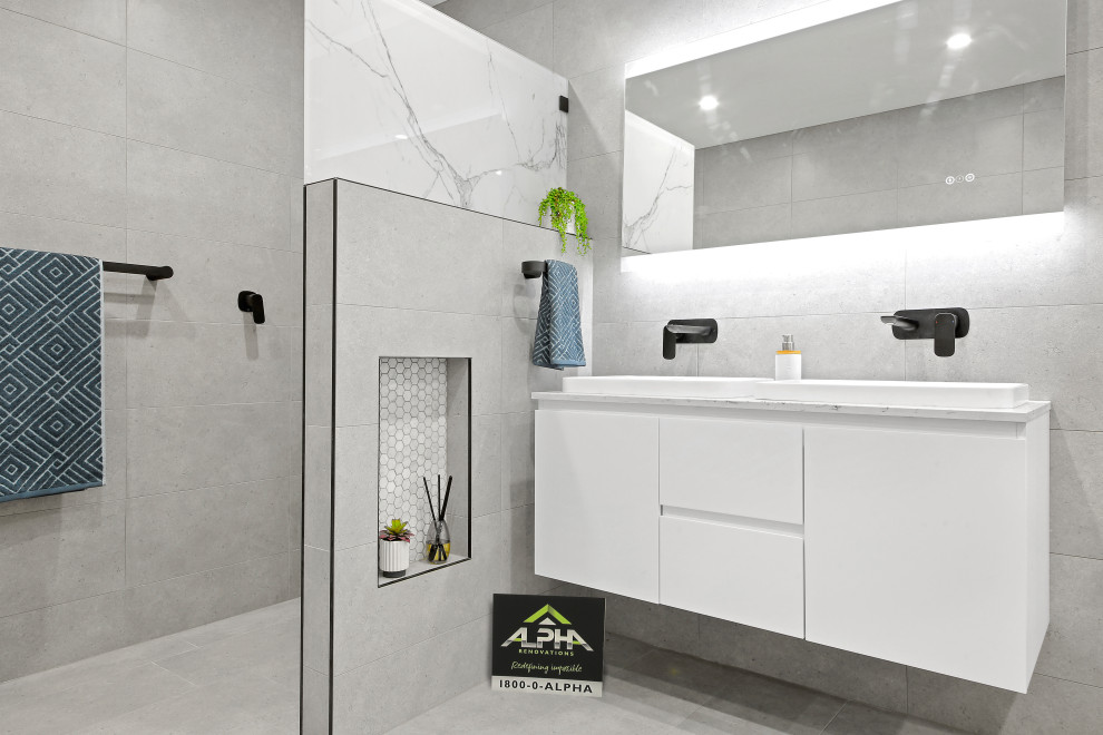 Exempel på ett mellanstort modernt vit vitt en-suite badrum, med släta luckor, vita skåp, ett fristående badkar, en öppen dusch, en vägghängd toalettstol, grå kakel, porslinskakel, grå väggar, klinkergolv i porslin, ett integrerad handfat, bänkskiva i kvarts, grått golv och med dusch som är öppen