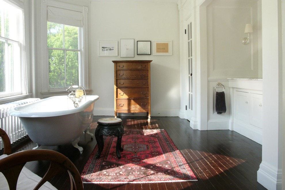 Inredning av ett klassiskt mycket stort en-suite badrum, med ett badkar med tassar, vita väggar, mörkt trägolv, vita skåp, ett undermonterad handfat, luckor med infälld panel och marmorbänkskiva