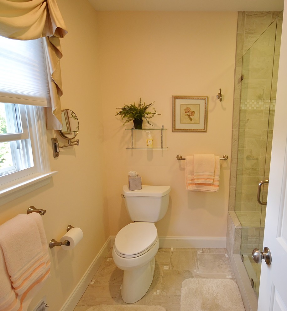 Corner shower - mid-sized traditional master beige tile and ceramic tile ceramic tile and beige floor corner shower idea in Philadelphia with recessed-panel cabinets, medium tone wood cabinets, a one-piece toilet, an undermount sink, granite countertops and a hinged shower door