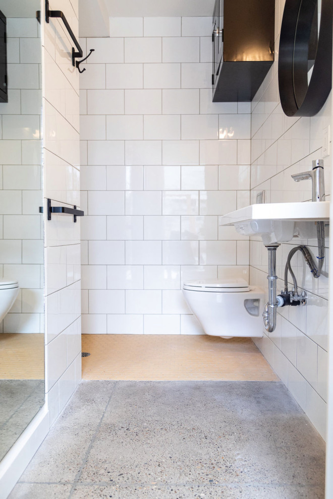 Foto på ett litet funkis badrum med dusch, med en öppen dusch, en vägghängd toalettstol, vit kakel, keramikplattor, vita väggar, betonggolv, ett väggmonterat handfat och grått golv