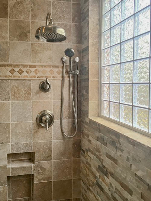 Bild på ett mellanstort skandinaviskt en-suite badrum, med ett fristående badkar, en dusch i en alkov, flerfärgad kakel, mosaik, bruna väggar, mosaikgolv, ett nedsänkt handfat, brunt golv och dusch med gångjärnsdörr
