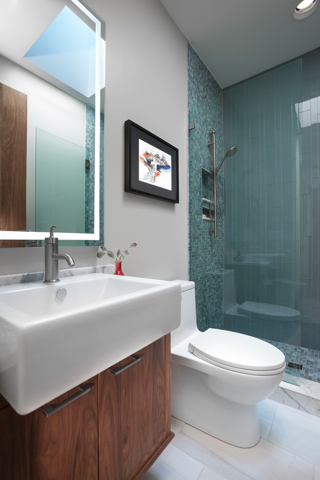 Photo of a contemporary bathroom in Other with flat-panel cabinets, medium wood cabinets, a walk-in shower, a one-piece toilet, blue tiles, glass tiles, white walls, porcelain flooring and a vessel sink.