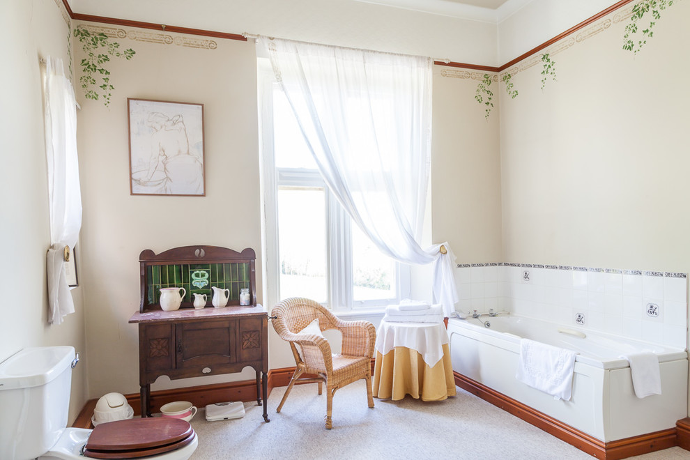Cette image montre une salle de bain traditionnelle avec une baignoire en alcôve, un mur beige et un placard avec porte à panneau encastré.
