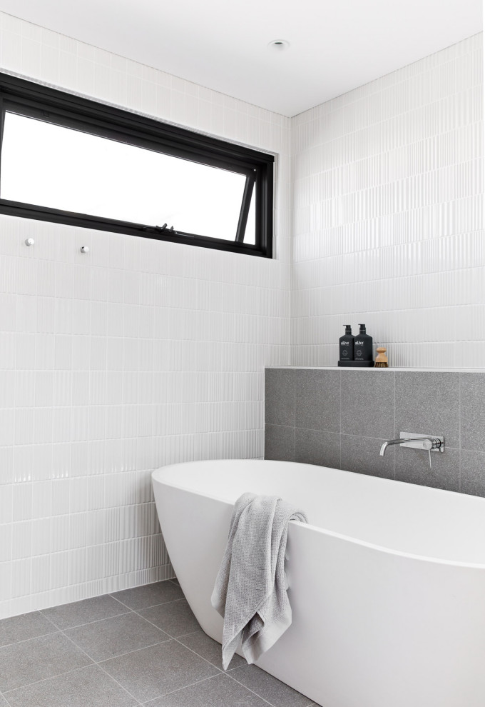 Свежая идея для дизайна: главная ванная комната среднего размера в современном стиле с светлыми деревянными фасадами, отдельно стоящей ванной, открытым душем, раздельным унитазом, белой плиткой, керамической плиткой, белыми стенами, полом из керамогранита, подвесной раковиной, серым полом, открытым душем, тумбой под две раковины и подвесной тумбой - отличное фото интерьера