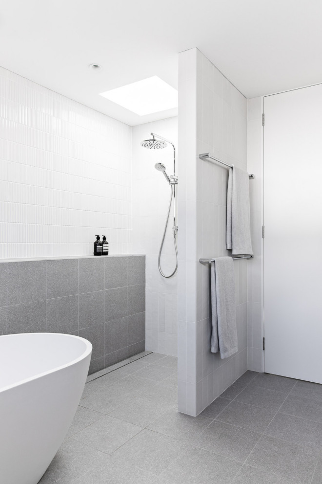 Idéer för att renovera ett mellanstort funkis en-suite badrum, med skåp i ljust trä, ett fristående badkar, en öppen dusch, en toalettstol med separat cisternkåpa, vit kakel, keramikplattor, vita väggar, klinkergolv i porslin, ett väggmonterat handfat, grått golv och med dusch som är öppen
