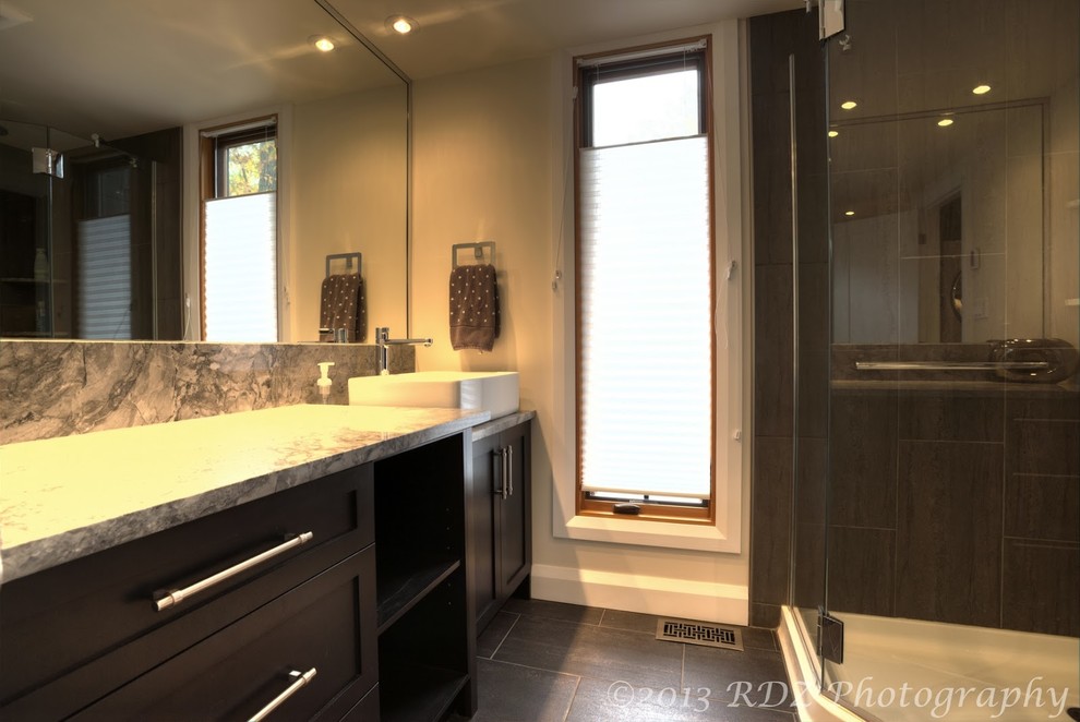 Immagine di una stanza da bagno design con lavabo a bacinella, ante in stile shaker, ante grigie, top in granito, doccia ad angolo, WC monopezzo, piastrelle grigie e piastrelle in gres porcellanato