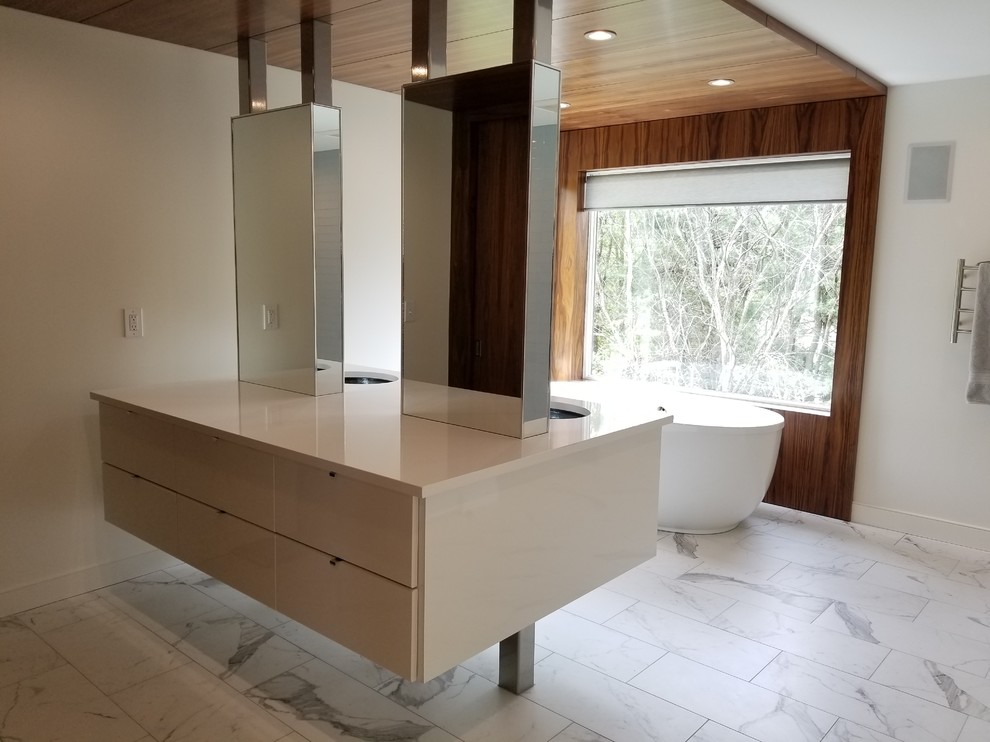 Large modern ensuite bathroom in Boston with flat-panel cabinets, white cabinets, a freestanding bath, a walk-in shower, a one-piece toilet, white tiles, porcelain tiles, white walls, porcelain flooring, a submerged sink, engineered stone worktops, white floors and an open shower.