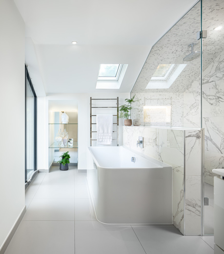 This is an example of a large contemporary ensuite bathroom in Berkshire with flat-panel cabinets, white cabinets, a built-in bath, a built-in shower, a wall mounted toilet, white tiles, porcelain tiles, white walls, porcelain flooring, a console sink, white floors, a hinged door, an enclosed toilet, double sinks and a floating vanity unit.