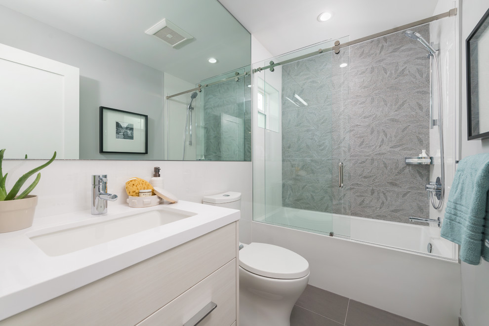 Modernes Badezimmer mit flächenbündigen Schrankfronten, beigen Schränken, Badewanne in Nische, Duschnische, Wandtoilette mit Spülkasten, grauen Fliesen, weißer Wandfarbe, Unterbauwaschbecken und Schiebetür-Duschabtrennung in San Francisco