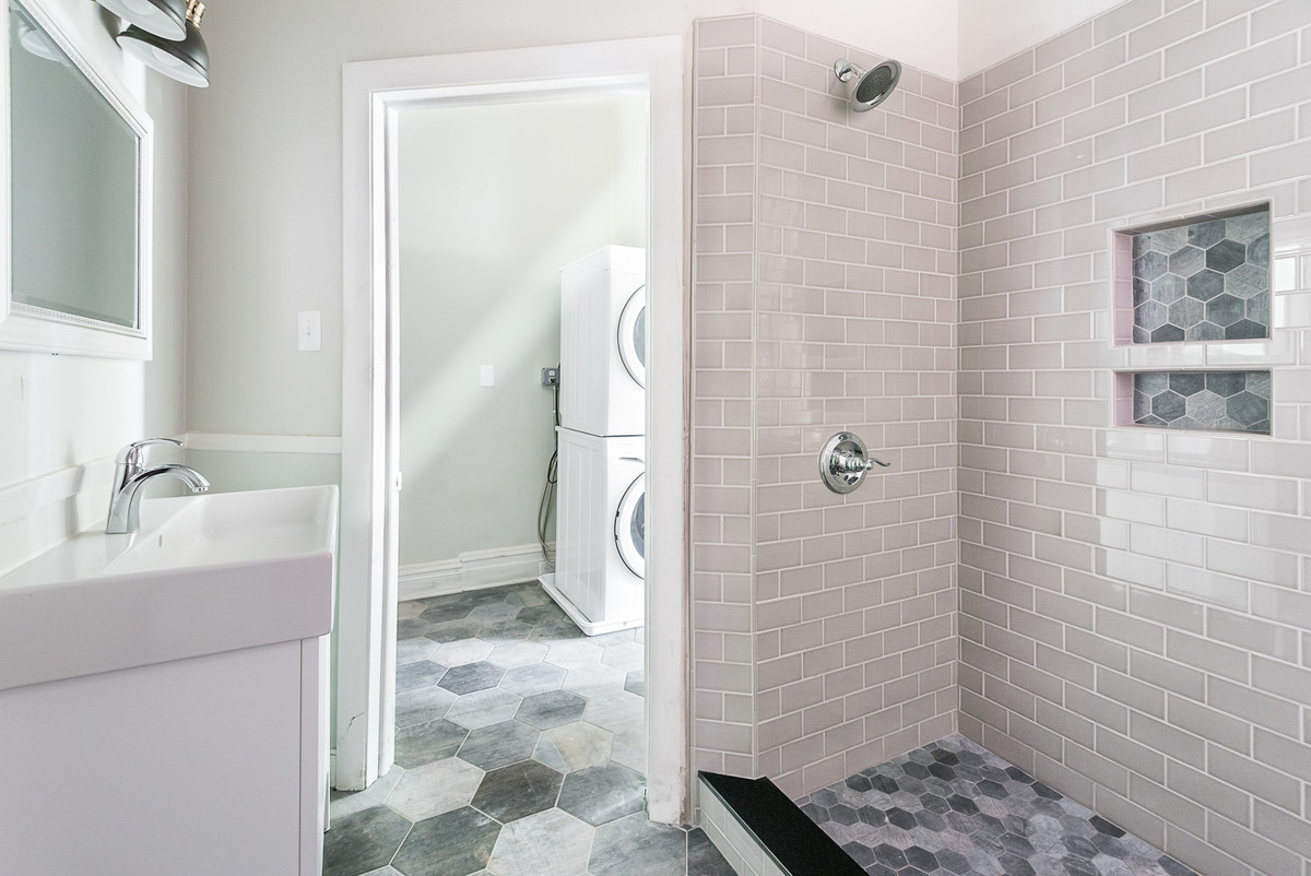 Modelo de cuarto de baño tradicional renovado con armarios con paneles lisos, puertas de armario blancas, baldosas y/o azulejos rosa, baldosas y/o azulejos de cemento, paredes grises, suelo de azulejos de cemento, aseo y ducha, lavabo integrado y suelo gris