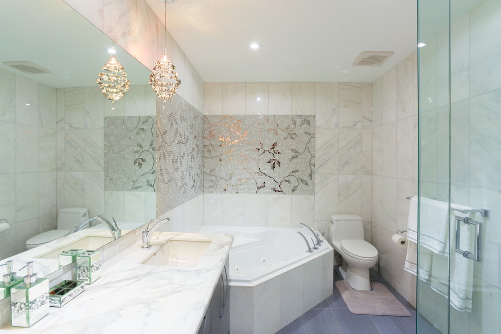 Свежая идея для дизайна: большая главная ванная комната в стиле неоклассика (современная классика) с врезной раковиной, угловой ванной, унитазом-моноблоком, белой плиткой, серыми фасадами, каменной плиткой, белыми стенами, полом из керамогранита, мраморной столешницей, плоскими фасадами, серым полом, душем в нише и душем с распашными дверями - отличное фото интерьера