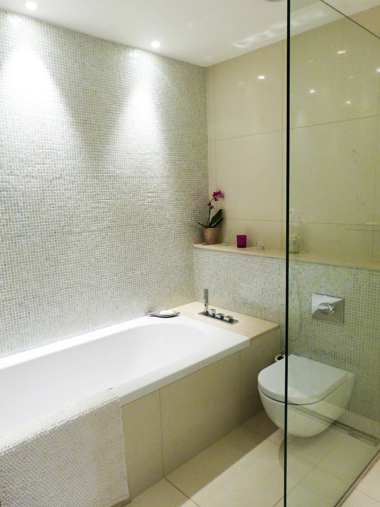Modernes Badezimmer En Suite mit integriertem Waschbecken, flächenbündigen Schrankfronten, dunklen Holzschränken, Einbaubadewanne, Eckdusche, Toilette mit Aufsatzspülkasten, grauen Fliesen, Mosaikfliesen, Porzellan-Bodenfliesen und beiger Wandfarbe in London