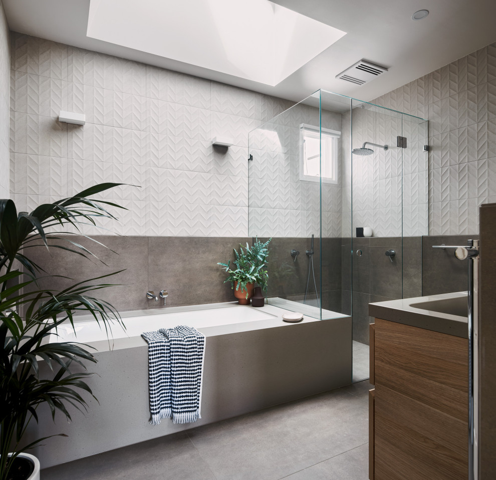 Свежая идея для дизайна: главная ванная комната среднего размера в современном стиле с светлыми деревянными фасадами, угловым душем, инсталляцией, керамической плиткой, полом из керамогранита, серым полом, душем с распашными дверями, серой столешницей, полновстраиваемой ванной, столешницей из искусственного камня, сиденьем для душа, белой плиткой, белыми стенами, врезной раковиной, тумбой под одну раковину и подвесной тумбой - отличное фото интерьера