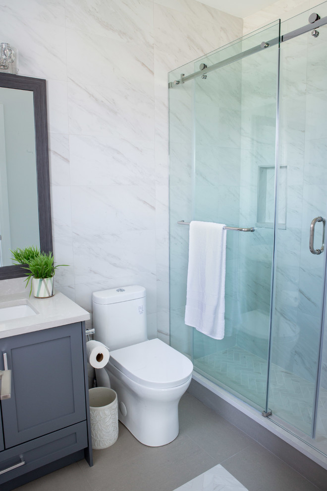 Пример оригинального дизайна: ванная комната среднего размера в современном стиле с фасадами в стиле шейкер, серыми фасадами, ванной в нише, душем в нише, раздельным унитазом, серой плиткой, мраморной плиткой, серыми стенами, полом из керамогранита, душевой кабиной, врезной раковиной, коричневым полом, душем с раздвижными дверями и бежевой столешницей
