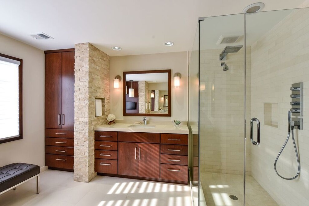Photo of a medium sized contemporary ensuite bathroom in DC Metro with flat-panel cabinets, medium wood cabinets, a two-piece toilet, beige tiles, stone tiles, beige walls, travertine flooring, a submerged sink, engineered stone worktops, an alcove shower, beige floors and a hinged door.