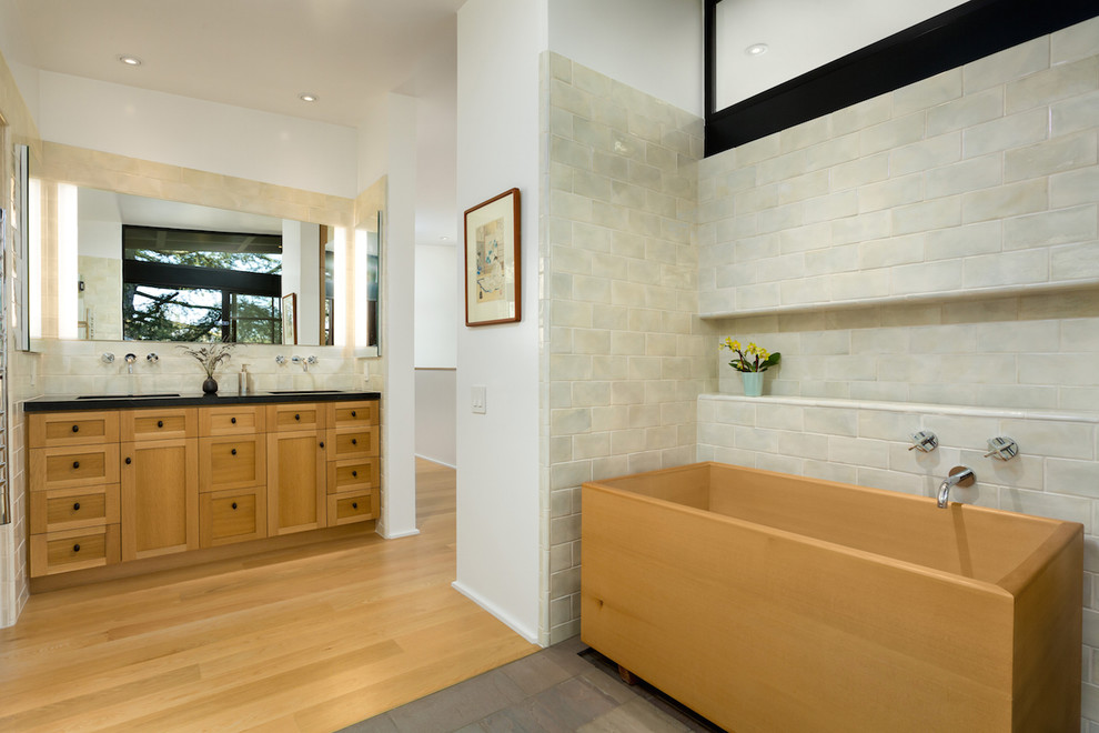 Example of a large transitional master ceramic tile and beige tile light wood floor japanese bathtub design in Los Angeles with shaker cabinets, light wood cabinets, white walls and soapstone countertops