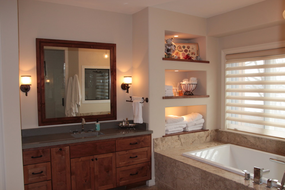 Design ideas for a large traditional bathroom in Milwaukee with an integrated sink, recessed-panel cabinets, medium wood cabinets, concrete worktops, a built-in bath, a walk-in shower, a one-piece toilet, beige tiles, metro tiles, white walls and ceramic flooring.