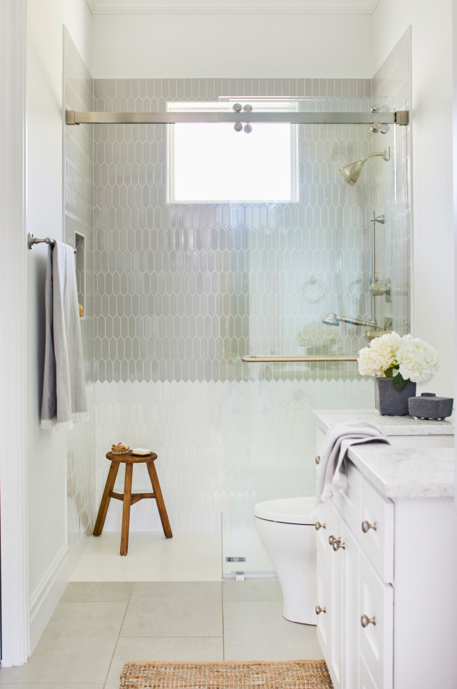 Пример оригинального дизайна: ванная комната в стиле неоклассика (современная классика) с фасадами в стиле шейкер, белыми фасадами, душем без бортиков, серой плиткой, белыми стенами, врезной раковиной, серым полом, душем с раздвижными дверями, белой столешницей, нишей, тумбой под одну раковину и встроенной тумбой