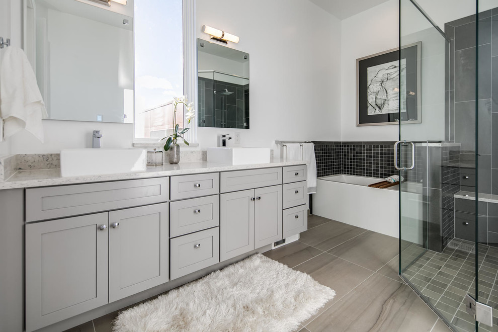 This is an example of a medium sized traditional ensuite bathroom in Denver with grey cabinets, an alcove bath, a corner shower, a one-piece toilet, beige tiles, stone tiles, white walls, ceramic flooring, a vessel sink, engineered stone worktops, brown floors, a hinged door and white worktops.