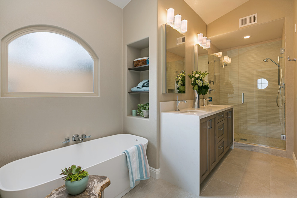 Photo of a medium sized classic ensuite bathroom in San Diego with shaker cabinets, brown cabinets, a freestanding bath, a double shower, a one-piece toilet, beige tiles, porcelain tiles, grey walls, porcelain flooring, a submerged sink, engineered stone worktops, grey floors and a hinged door.
