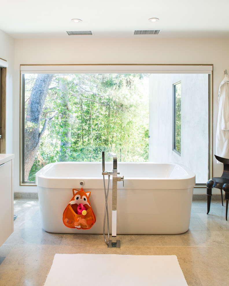 ロサンゼルスにある広いコンテンポラリースタイルのおしゃれなマスターバスルーム (置き型浴槽、フラットパネル扉のキャビネット、白いキャビネット、珪岩の洗面台、ベージュの床) の写真