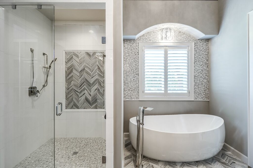 This is an example of a large contemporary ensuite bathroom in Kansas City with a freestanding bath, a corner shower and grey tiles.
