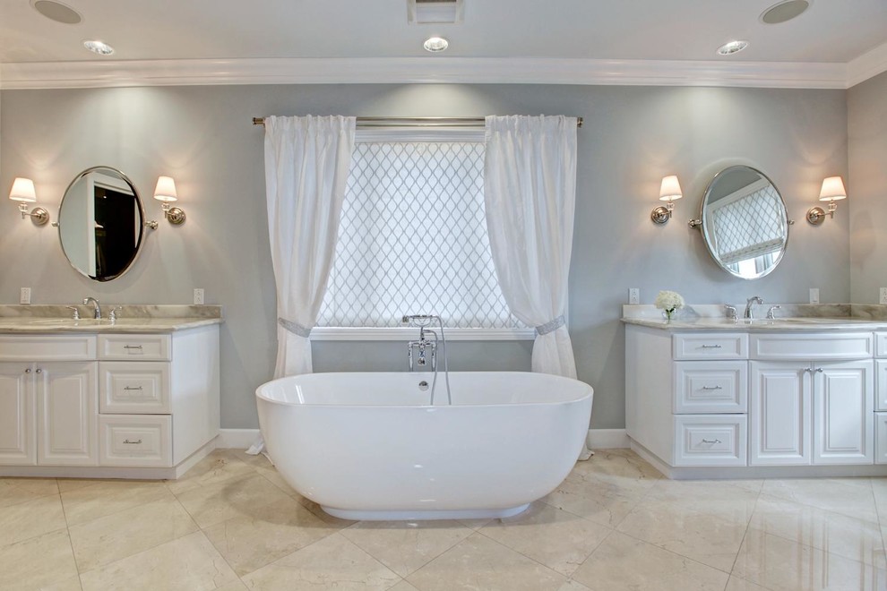 Großes Modernes Badezimmer En Suite mit profilierten Schrankfronten, weißen Schränken, freistehender Badewanne, beigen Fliesen, grauer Wandfarbe, Kalkstein, Unterbauwaschbecken und Quarzwerkstein-Waschtisch in Orange County