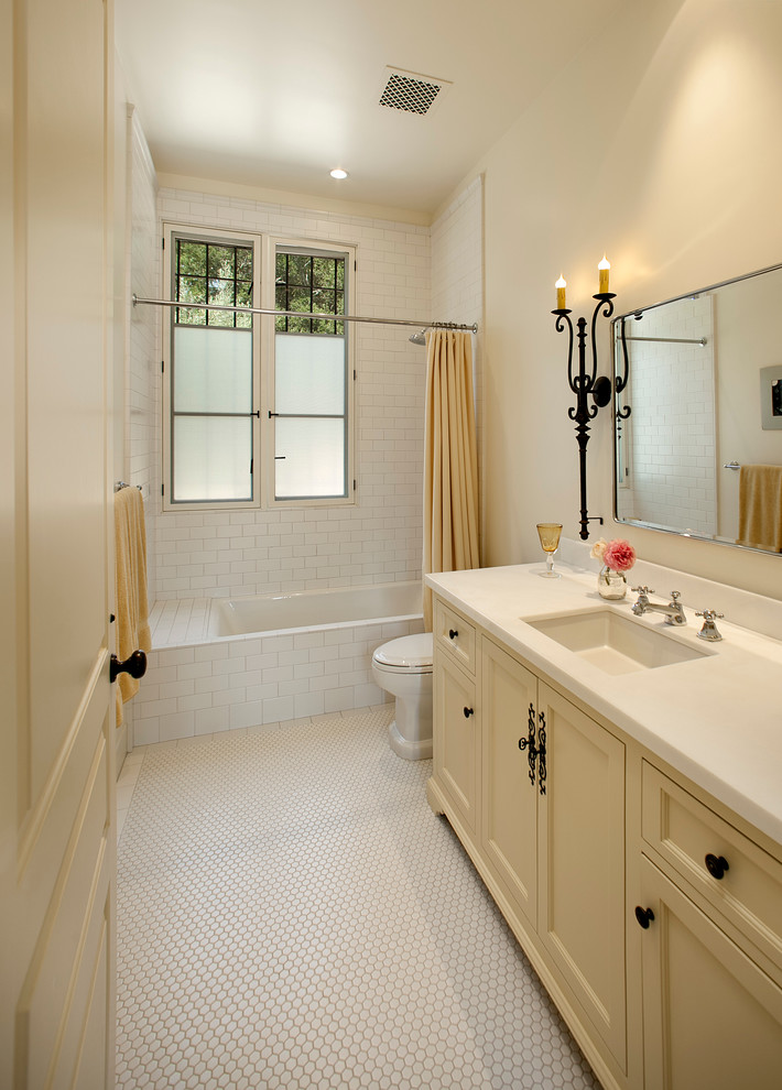 Idéer för mellanstora medelhavsstil badrum, med luckor med infälld panel, gula skåp, ett badkar i en alkov, en dusch/badkar-kombination, en toalettstol med hel cisternkåpa, vit kakel, beige väggar, klinkergolv i keramik och ett undermonterad handfat