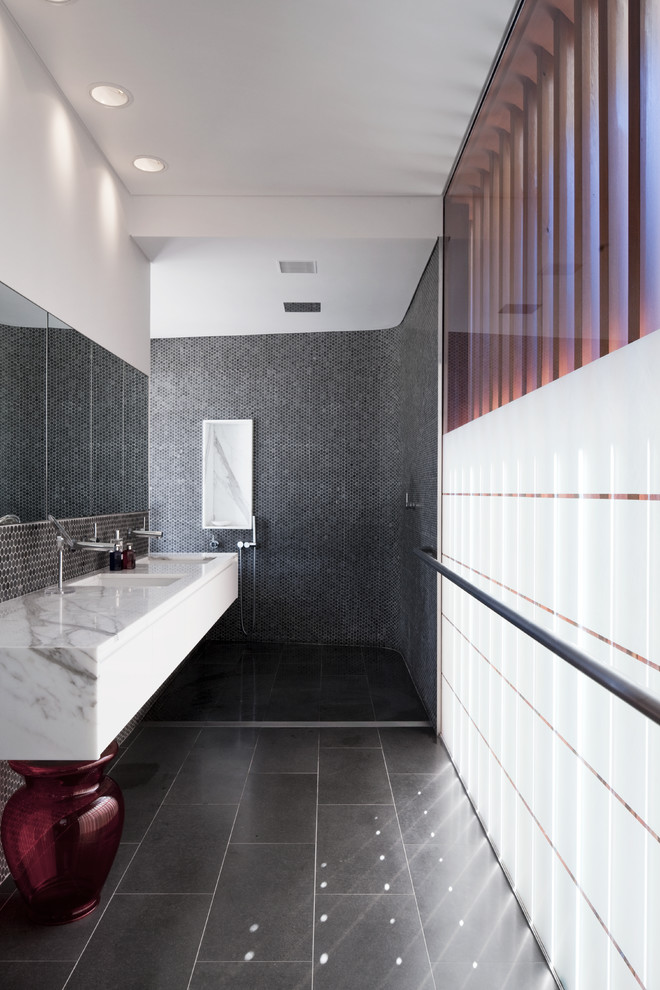 Cette image montre une salle de bain design avec un lavabo suspendu, un plan de toilette en marbre, un carrelage noir, un mur blanc et un sol en ardoise.