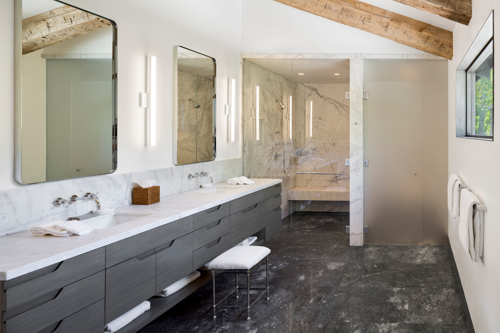 Inredning av ett modernt stort en-suite badrum, med ett undermonterad handfat, släta luckor, grå skåp, marmorbänkskiva, en kantlös dusch, en toalettstol med hel cisternkåpa, vit kakel, stenhäll, vita väggar och marmorgolv