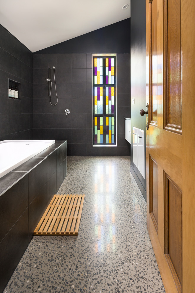 Diseño de cuarto de baño bohemio de tamaño medio con bañera encastrada, paredes negras, suelo de cemento y ducha abierta