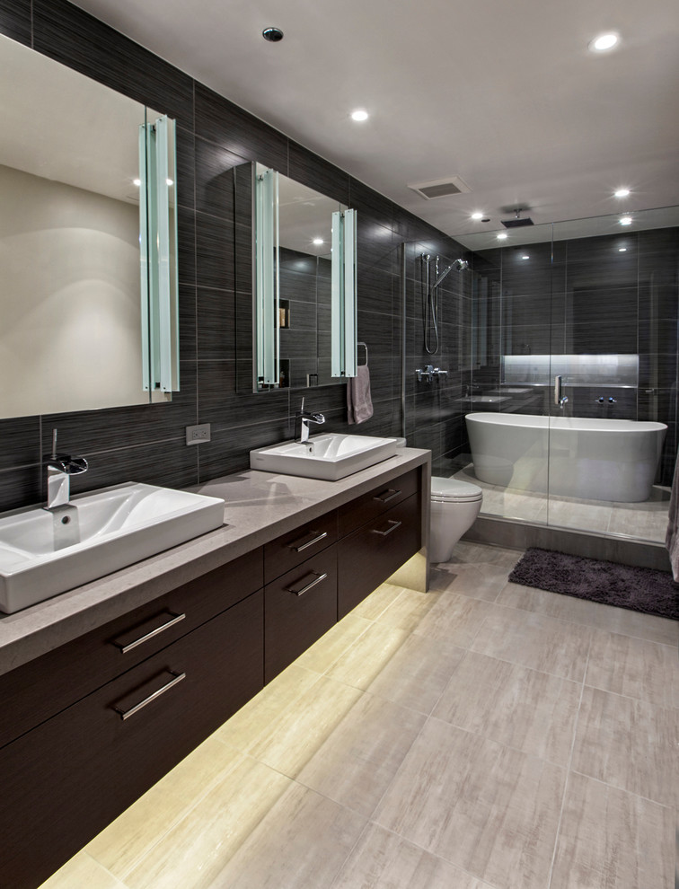 Inspiration for a large contemporary ensuite bathroom in Chicago with a wall-mounted sink, flat-panel cabinets, dark wood cabinets, engineered stone worktops, a freestanding bath, an alcove shower, grey tiles, ceramic tiles and black walls.