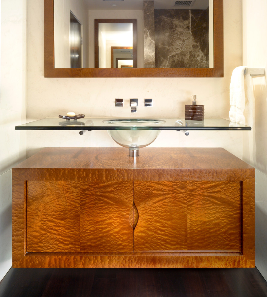Inredning av ett modernt litet badrum, med möbel-liknande, skåp i mellenmörkt trä, mörkt trägolv, bänkskiva i glas och ett undermonterad handfat