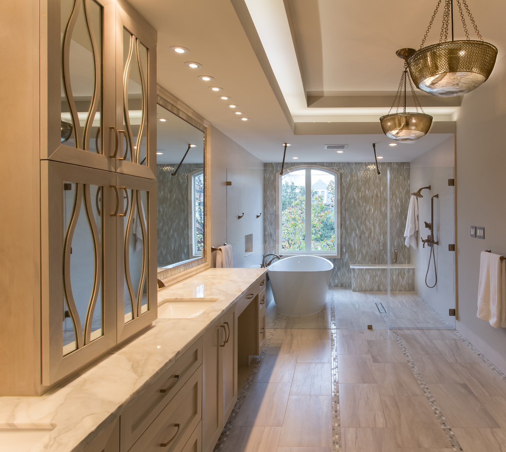 This is an example of a large classic ensuite bathroom in Houston with a submerged sink, freestanding cabinets, white cabinets, marble worktops, a freestanding bath, a shower/bath combination, a two-piece toilet, grey tiles, porcelain tiles, grey walls, porcelain flooring, a hinged door, grey worktops and grey floors.