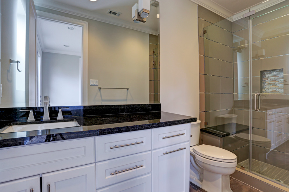 ヒューストンにあるラグジュアリーな広いトランジショナルスタイルのおしゃれなバスルーム (浴槽なし) (アンダーカウンター洗面器、落し込みパネル扉のキャビネット、白いキャビネット、御影石の洗面台、コーナー型浴槽、シャワー付き浴槽	、分離型トイレ、グレーのタイル、セラミックタイル、グレーの壁、セラミックタイルの床) の写真
