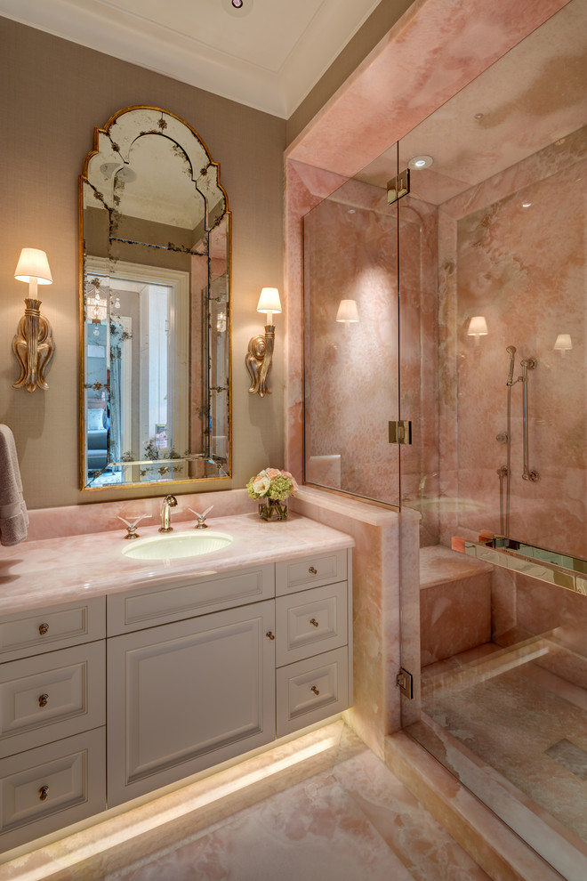 Источник вдохновения для домашнего уюта: главная ванная комната в стиле неоклассика (современная классика) с фасадами с выступающей филенкой, белыми фасадами, душем в нише, розовой плиткой, мраморной плиткой, бежевыми стенами, мраморным полом, врезной раковиной, столешницей из оникса, розовым полом, душем с распашными дверями и розовой столешницей