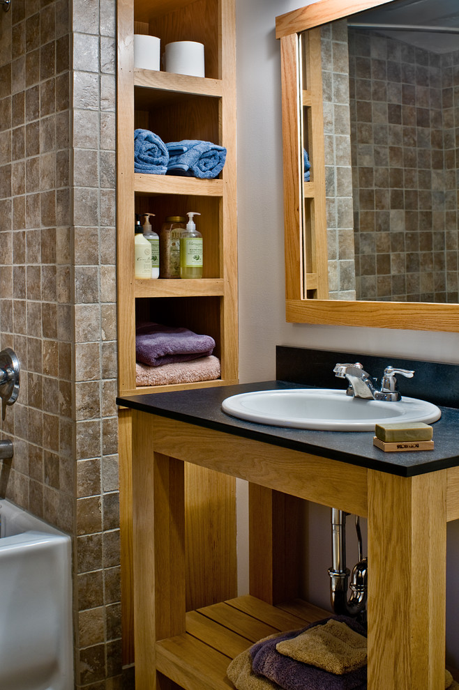 Идея дизайна: большая главная ванная комната в современном стиле с настольной раковиной, светлыми деревянными фасадами, столешницей из оникса, угловой ванной, серыми стенами и полом из керамической плитки