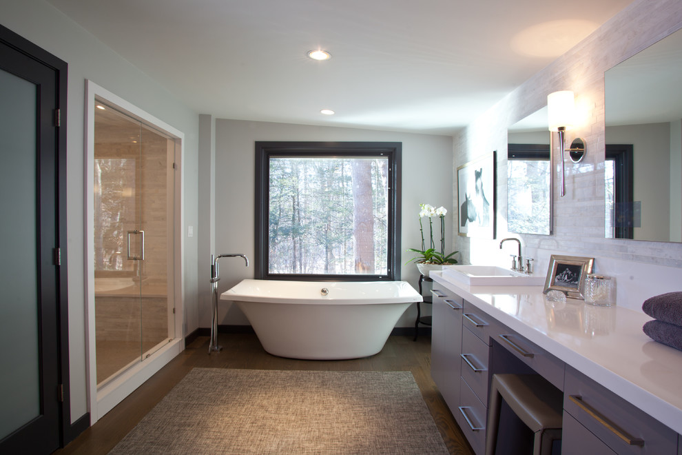 Example of a large trendy master dark wood floor and brown floor bathroom design in New York with flat-panel cabinets, gray cabinets, gray walls, a vessel sink, solid surface countertops, a hinged shower door and white countertops