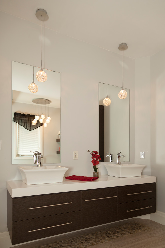 На фото: ванная комната в современном стиле с плоскими фасадами, темными деревянными фасадами, галечной плиткой, белыми стенами, настольной раковиной и столешницей из искусственного кварца с