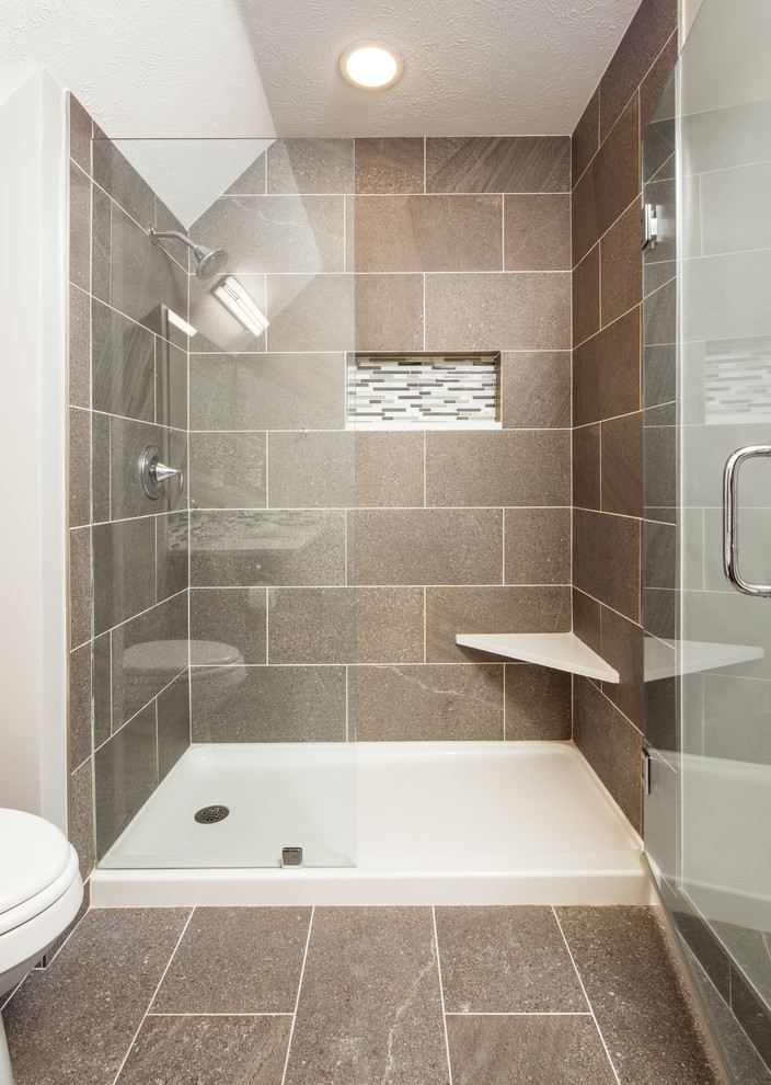 Mid-sized transitional master brown tile and ceramic tile ceramic tile and brown floor alcove shower photo in Omaha with recessed-panel cabinets, medium tone wood cabinets, a two-piece toilet, white walls, an undermount sink, solid surface countertops, a hinged shower door and multicolored countertops