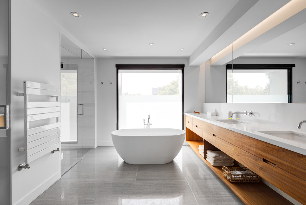 Design ideas for a medium sized contemporary ensuite bathroom in Toronto with flat-panel cabinets, medium wood cabinets, a freestanding bath, an alcove shower, white walls, a submerged sink, metro tiles, marble flooring, solid surface worktops and a hinged door.