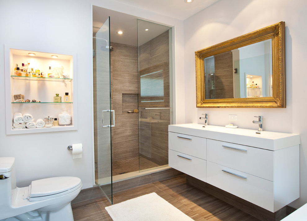 Design ideas for a medium sized contemporary ensuite bathroom in Toronto with flat-panel cabinets, white cabinets, an alcove shower, a one-piece toilet, brown tiles, a trough sink, porcelain tiles, white walls, porcelain flooring, solid surface worktops and brown floors.