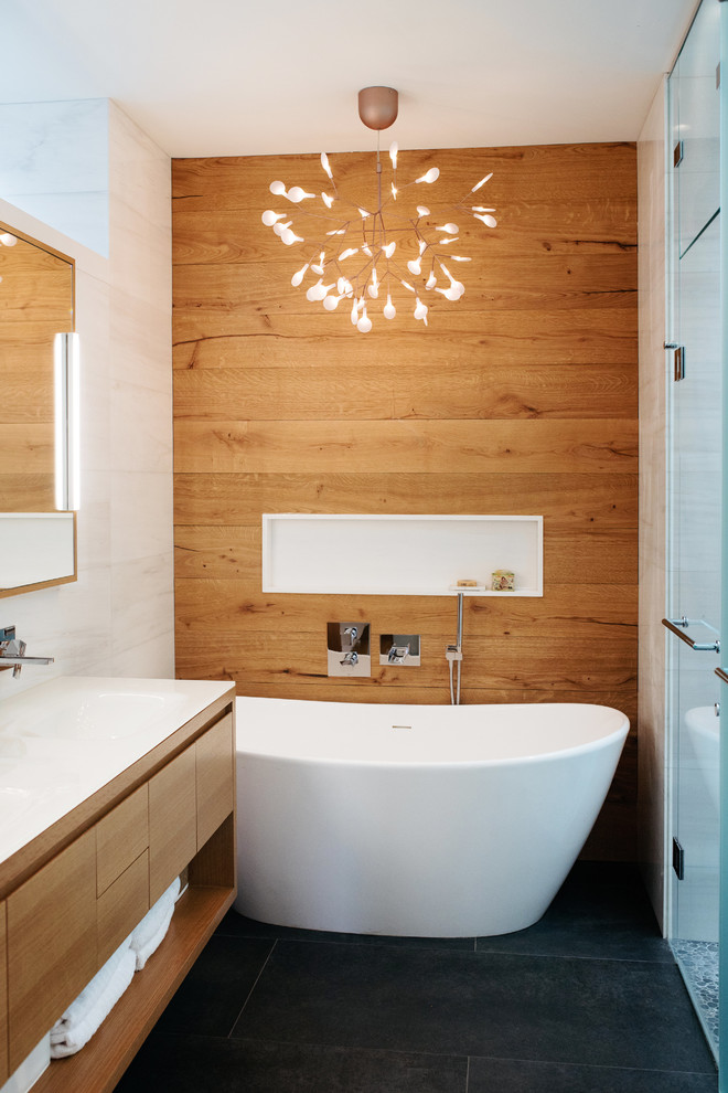 Свежая идея для дизайна: ванная комната в современном стиле с плоскими фасадами, фасадами цвета дерева среднего тона, отдельно стоящей ванной, душем без бортиков, белой плиткой, белыми стенами, монолитной раковиной, серым полом и душем с распашными дверями - отличное фото интерьера