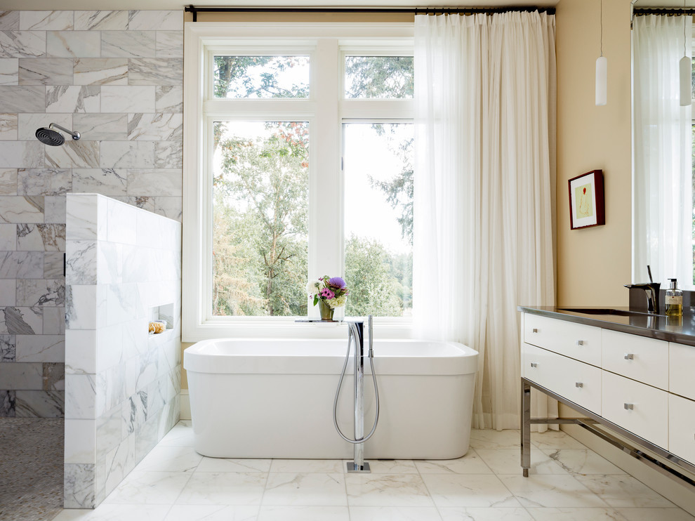 This is an example of a contemporary ensuite bathroom in Portland with flat-panel cabinets, white cabinets, a freestanding bath, a built-in shower, beige walls, a console sink, white floors and an open shower.