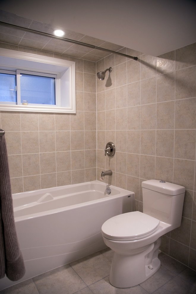 Photo of a medium sized traditional bathroom with an alcove bath, a shower/bath combination, a one-piece toilet, beige tiles, beige walls, beige floors, a shower curtain, shaker cabinets, brown cabinets and a built-in sink.