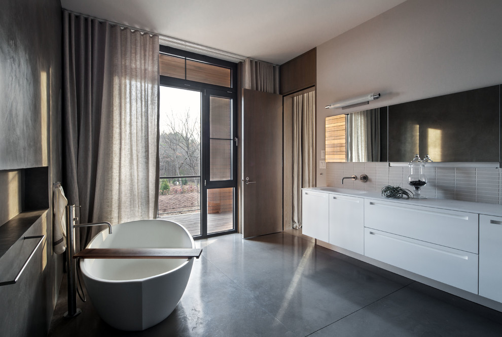 Exempel på ett modernt badrum, med ett fristående badkar och betonggolv