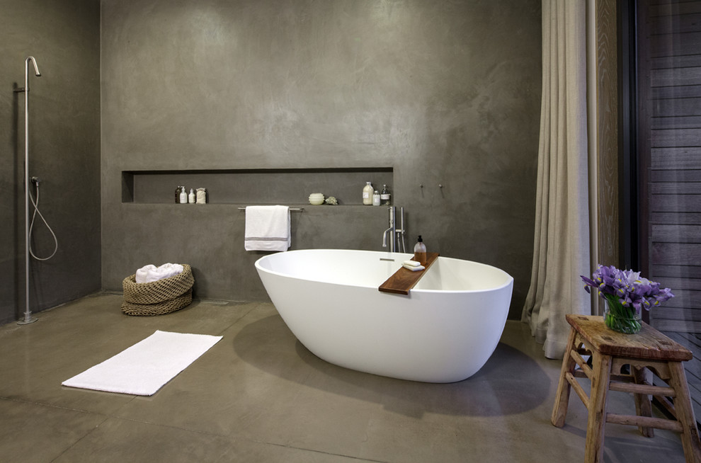 Modelo de cuarto de baño principal contemporáneo grande con lavabo suspendido, bañera exenta, ducha a ras de suelo, sanitario de pared, paredes grises y suelo de cemento