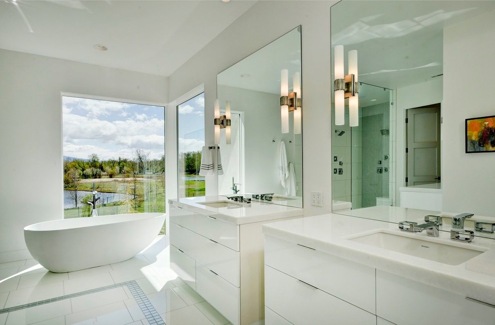 ボイシにあるコンテンポラリースタイルのおしゃれな浴室 (フラットパネル扉のキャビネット、白いキャビネット、置き型浴槽、白いタイル、白い洗面カウンター) の写真