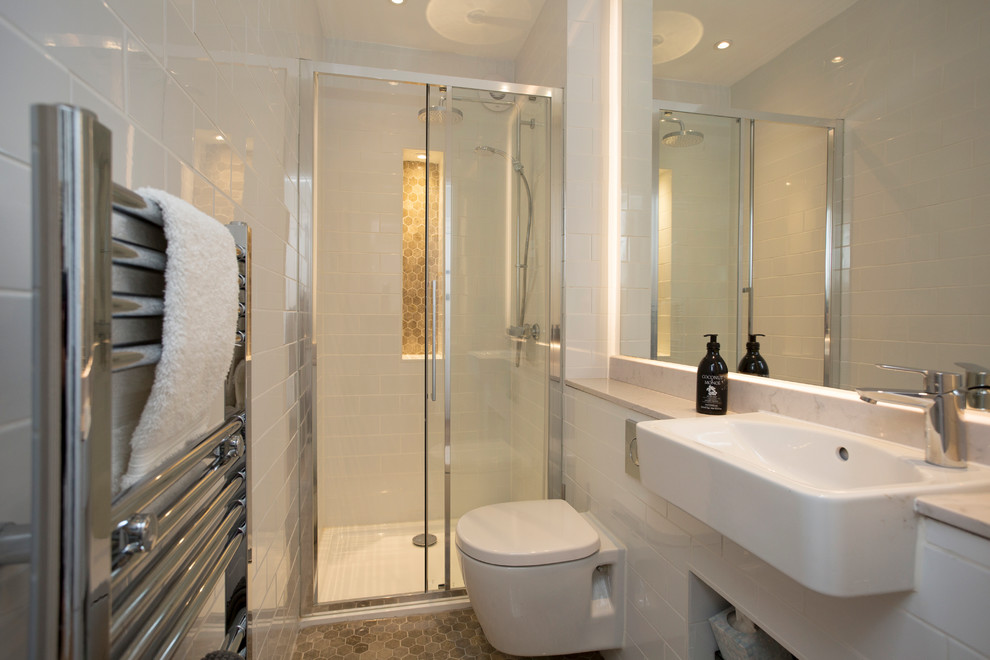 Photo of a small contemporary shower room bathroom in London with a wall mounted toilet, white tiles, white walls, grey floors, a sliding door, grey worktops, an alcove shower, metro tiles and an integrated sink.
